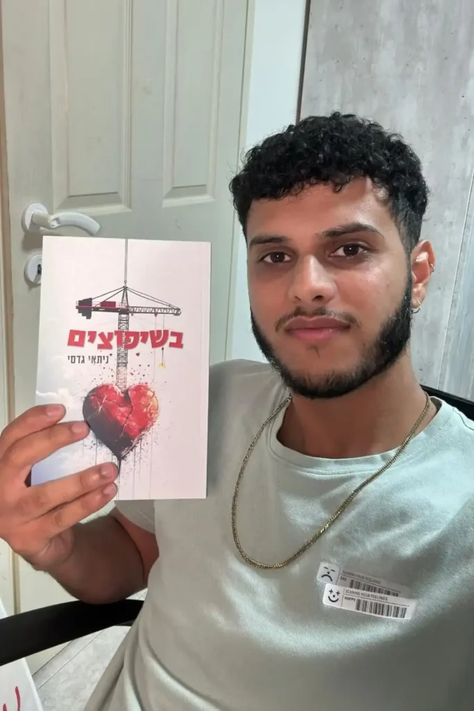 ניתאי גדסי מחזיק את ספרו ״בשיפוצים״